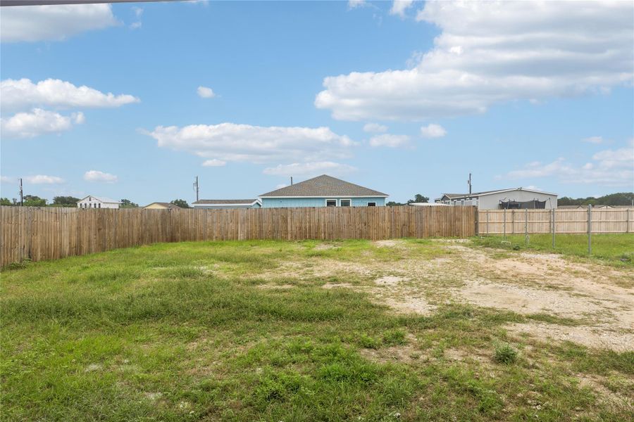 A spacious, fenced yard offers ample outdoor living potential under wide-open skies.