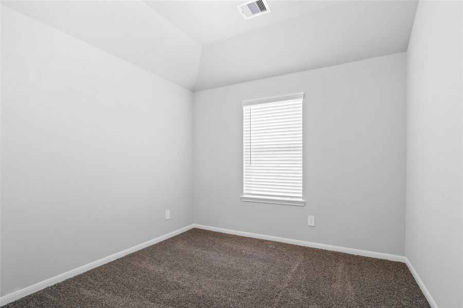 This inviting secondary bedroom combines comfort and modern elegance, featuring plush carpeting, a neutral color palette, closet, and abundant natural light streaming through a large window.