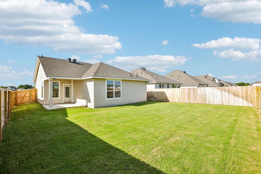 Green sod frames a classic shingle roofline and a fully wood-fenced property exterior.