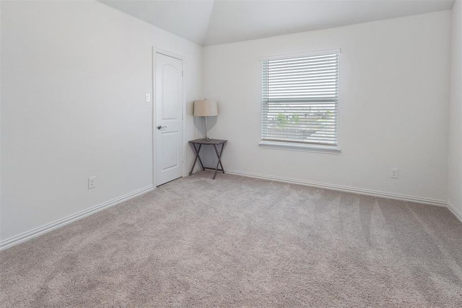Empty room with light carpet and vaulted ceiling