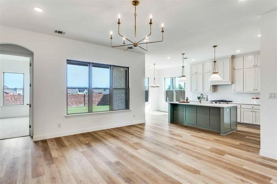 Kitchen with a chandelier, white cabinets, a kitchen island with sink, recessed lighting, and light countertops Kitchen with a chandelier, white cabinets, a kitchen island with sink, recessed lighting, and light countertops