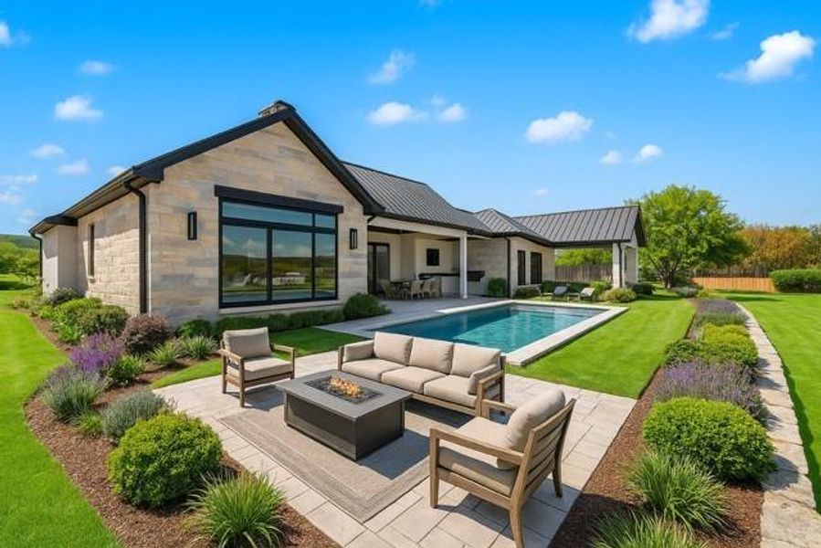 Rear view of property featuring an outdoor living space with a fire pit, a patio, stone siding, and a standing seam roof. Photo to show pool completion and possible landscape as per plan.