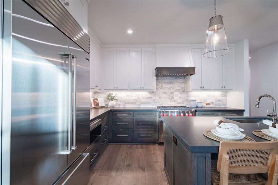 Kitchen with sink, high end appliances, white cabinetry, tasteful backsplash, and dark hardwood / wood-style flooring