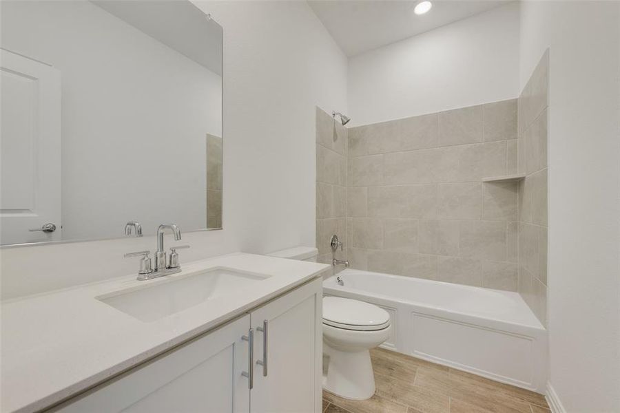 Full bathroom featuring vanity, tiled shower / bath combo, and toilet