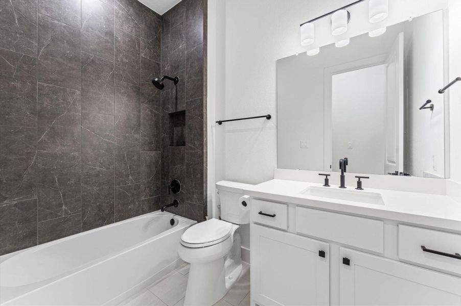 The primary bath brings the spa home — floor-to-ceiling dark tile in the walk-in shower, double vanity, and finishes that feel intentional.