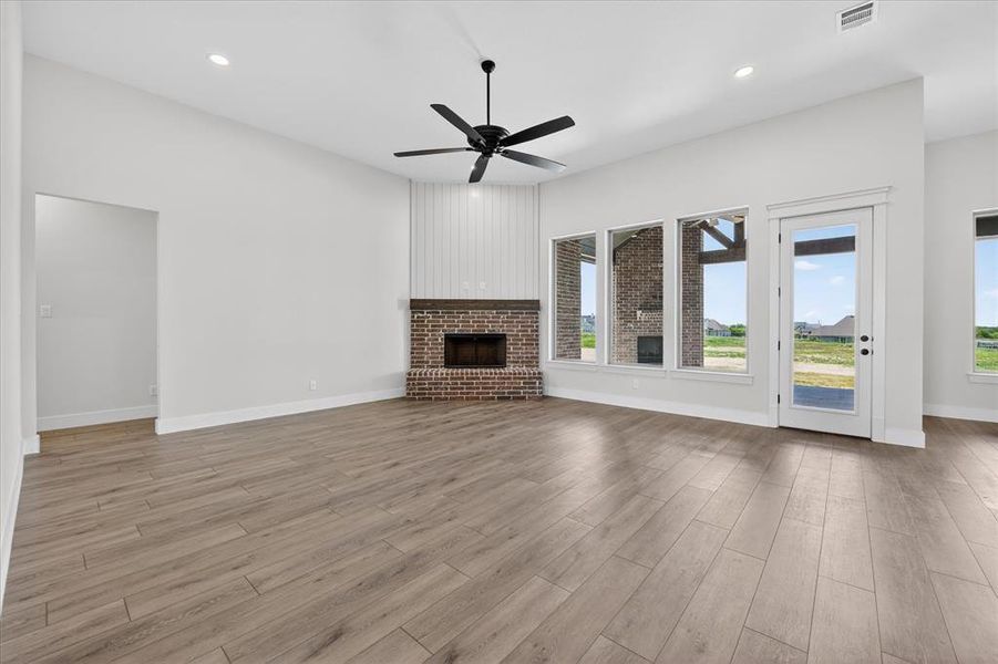 Unfurnished living room with a ceiling fan, a brick fireplace, recessed lighting, and light wood finished floors