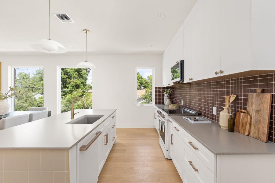 A contemporary kitchen space boasts sleek countertops, white cabinetry, and a charming tiled backsplash. A contemporary kitchen space boasts sleek countertops, white cabinetry, and a charming tiled backsplash.