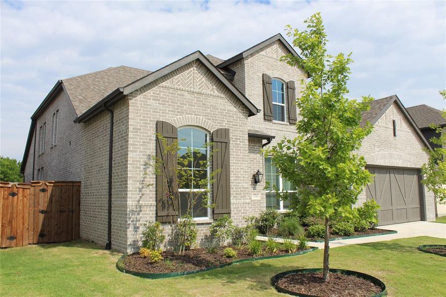 French country style house featuring brick siding, concrete driveway, roof with shingles, a gate, and a garage