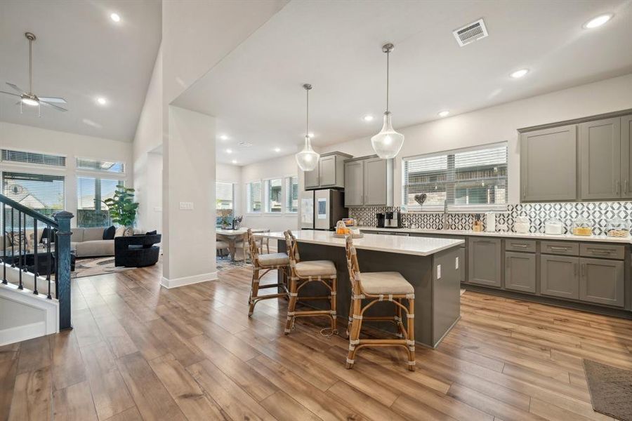 Kitchen featuring a breakfast bar, pendant lighting, light hardwood / wood-style floors, a kitchen island, and stainless steel refrigerator