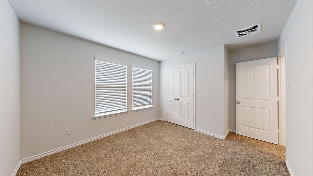 Room featuring neutral-toned carpeting, light gray walls, and two windows with blinds Room featuring neutral-toned carpeting, light gray walls, and two windows with blinds
