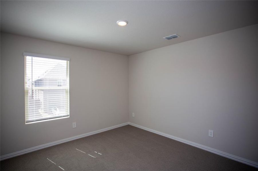 Unfurnished room with visible vents, baseboards, and dark carpet