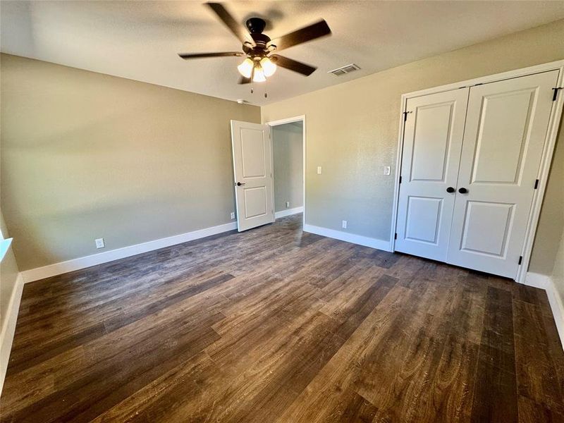 Unfurnished bedroom featuring dark wood-style flooring, a ceiling fan, and a closet