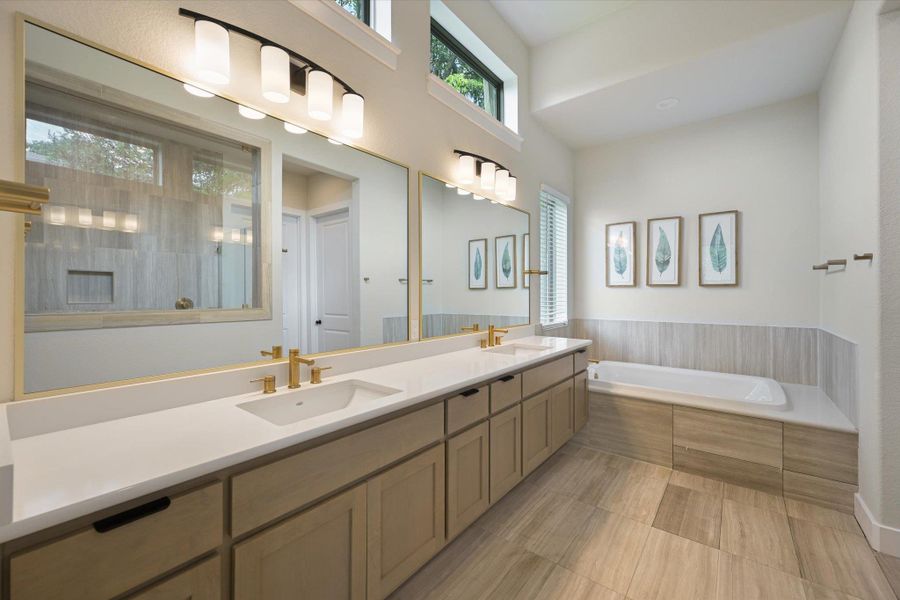 Well-lit primary bath features a spacious double vanity and built-in soaking tub, perfect for unwinding.