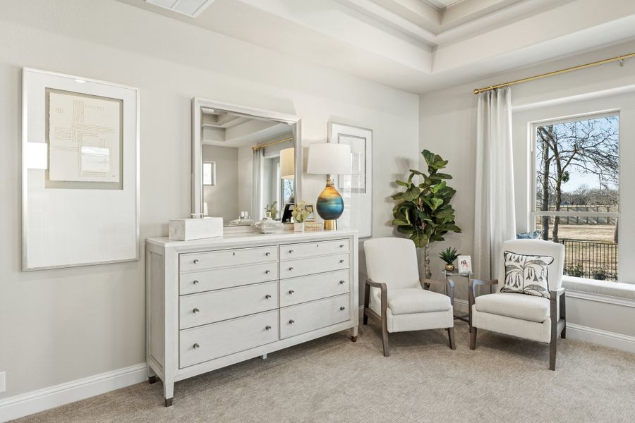 Bedroom sitting area with white dresser, mirror, two accent chairs, and tray ceiling near large window Bedroom sitting area with white dresser, mirror, two accent chairs, and tray ceiling near large window