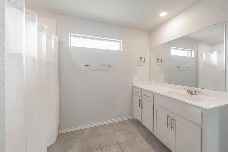 Bathroom featuring a double vanity with white cabinetry, integrated sinks, and a full-width wall mirror