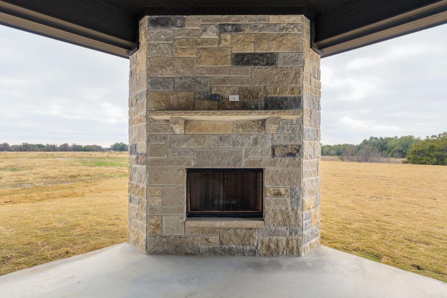 View of patio / terrace with an outdoor stone fireplace and a rural view
