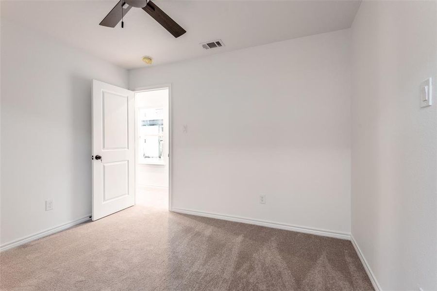 Carpeted empty room featuring ceiling fan