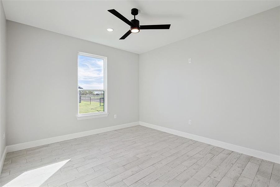 Empty room with ceiling fan and light hardwood / wood-style floors