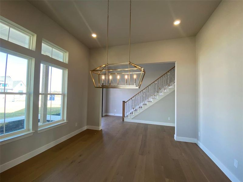 Unfurnished dining area with stairway, dark wood-type flooring, a chandelier, and recessed lighting