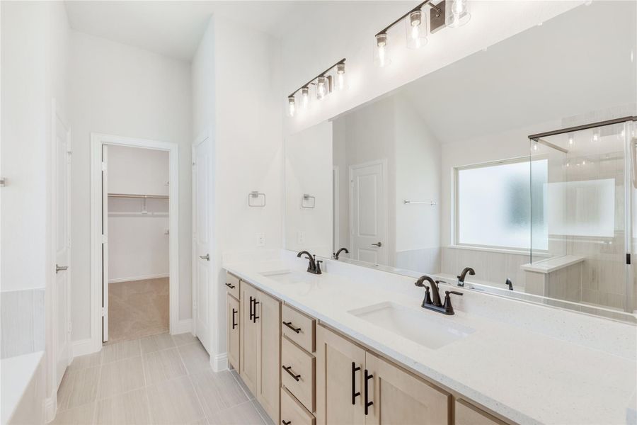 Master bathroom with double vanity, white quartz countertops, and walk-in closet entrance visible in background.