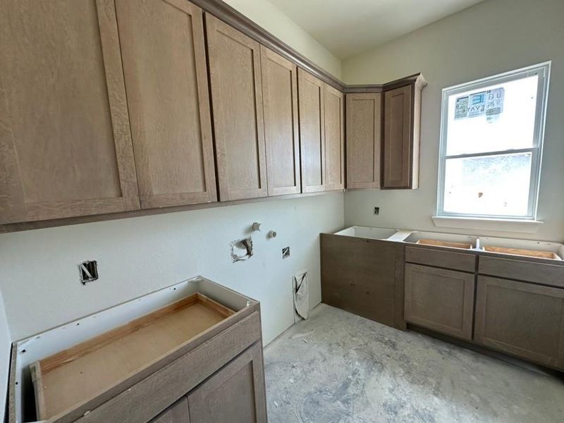Unfinished interior space featuring light wood-finish cabinetry, a corner upper cabinet, and an exposed window