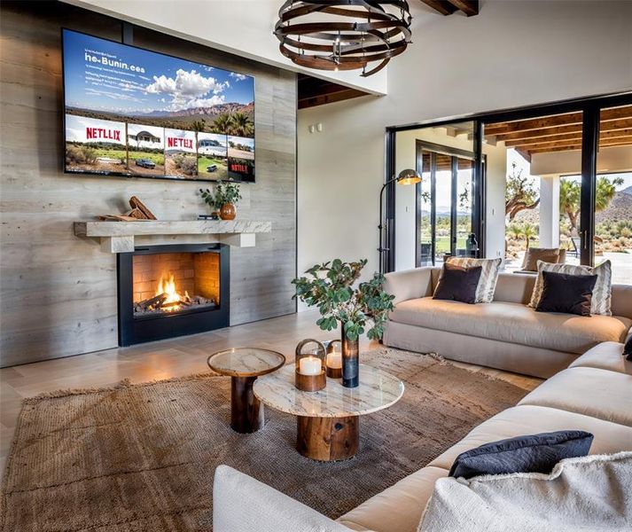 Living room featuring a chandelier, beam ceiling, wood finished floors, and a high end fireplace