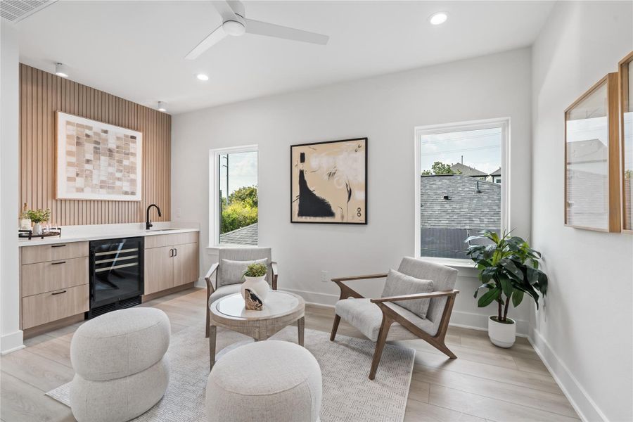 Upstairs, you’re greeted by a stylish secondary living area that continues the home’s Scandinavian-inspired design. A wet bar and fluted wood panel accent wall add both functionality and visual warmth, creating a perfect space for entertaining or relaxing. This thoughtful layout makes the upper level feel like a private retreat within the home.