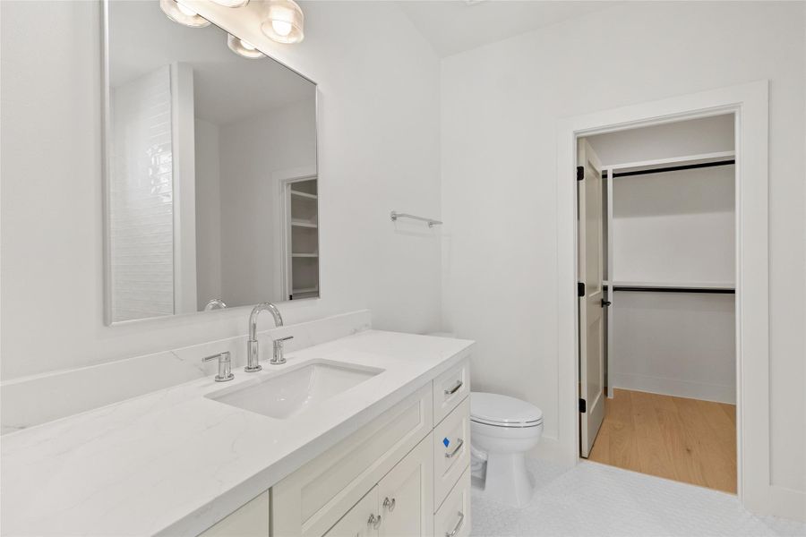 This bathroom feels fresh and thoughtfully designed, featuring a spacious vanity with quartz counters and modern fixtures, plus direct access to the walk-in closet for added convenience. The layout flows effortlessly, making mornings smoother and everyday routines feel more refined.