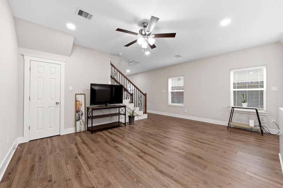 Light filled living room features durable laminate wood flooring, recessed lighting, and a ceiling fan.
