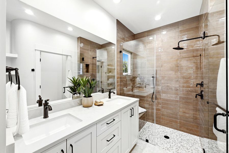 A well-appointed bathroom offers a dual-sink vanity and an oversized, glass-enclosed shower with multiple showerheads. A well-appointed bathroom offers a dual-sink vanity and an oversized, glass-enclosed shower with multiple showerheads.