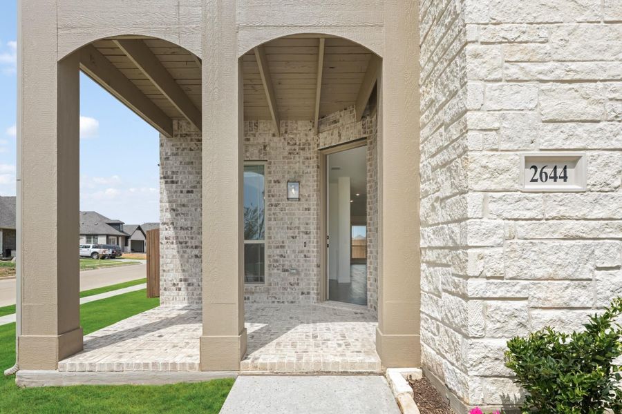 Covered front entry with arched columns, brick exterior, and glass front door at house number 2644