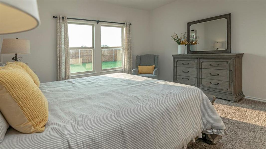 Bedroom featuring white walls, carpet flooring, and a double window looking out to a fenced backyard