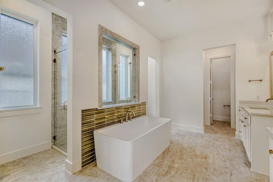 Bathroom featuring a freestanding tub, a shower stall, vanity, and recessed lighting