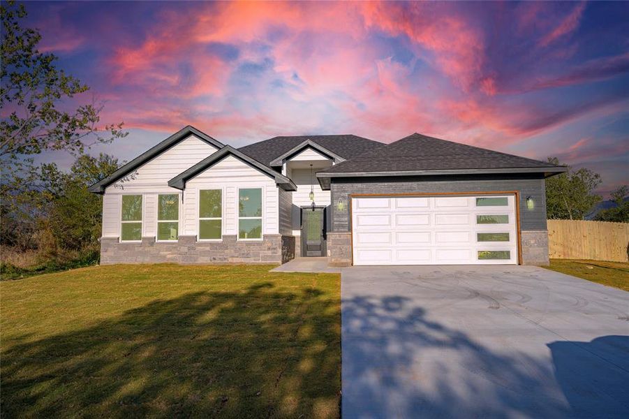 View of front facade featuring a lawn and a garage