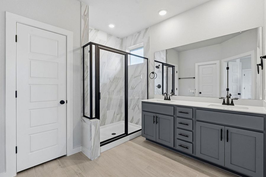 A well-lit bathroom showcases a glass-enclosed shower alongside a double vanity, offering a serene start to your day.