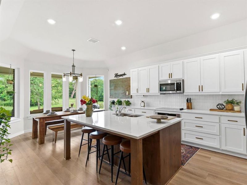 Farmhouse-inspired kitchen with ample cabinetry, generous counter space, and open sightlines to living area.