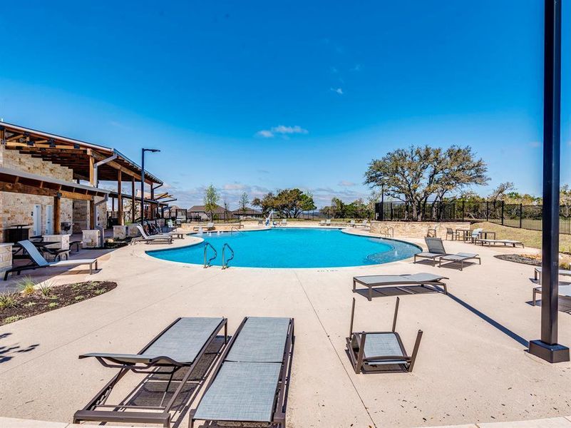 A spacious resort-style pool with ample lounging areas awaits beneath a clear sky.