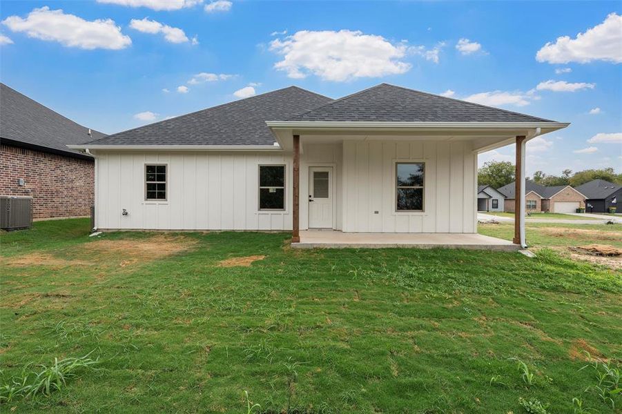 Rear view of property with a shingled roof, a yard, a patio, and board and batten siding