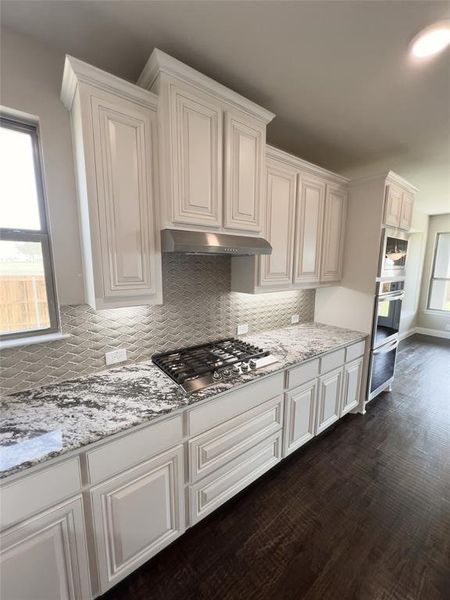 Kitchen with dark hardwood / wood-style floors, white cabinets, and gas stovetop