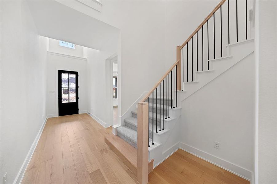 Entrance foyer featuring light wood finished floors, stairs, and a towering ceiling Entrance foyer featuring light wood finished floors, stairs, and a towering ceiling