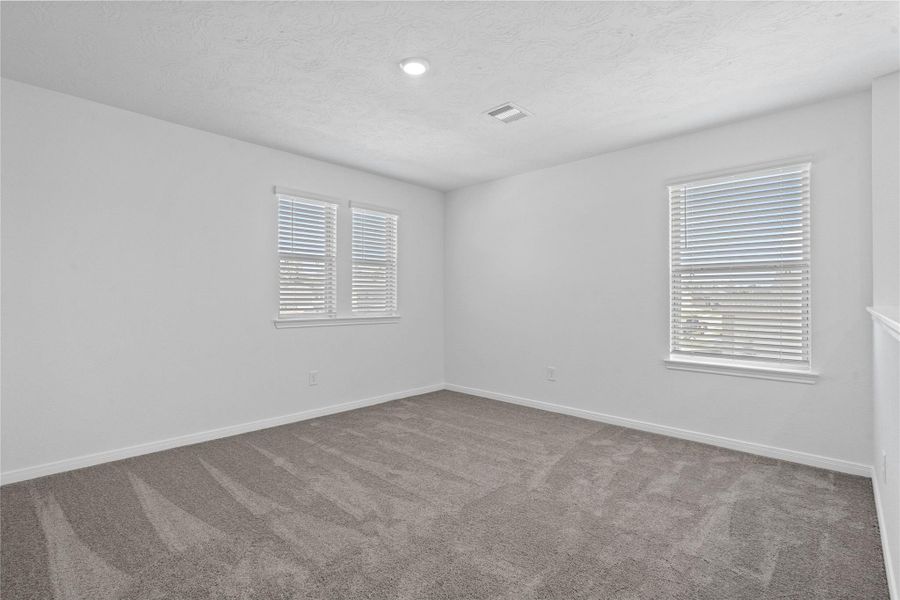 Come upstairs and enjoy a day of leisure in this fabulous and spacious game room! This is the perfect hangout spot or adult game room, this space features plush carpet, high ceiling, recessed lighting, custom paint and plenty of windows that will add natural light!