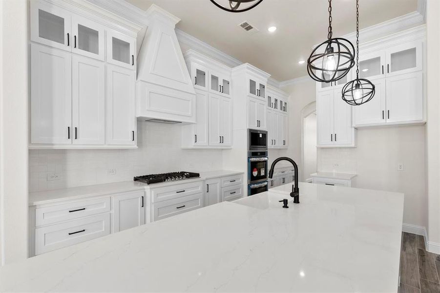 Kitchen featuring granite countertops, premium range hood, white custom cabinets, steel appliances , double ovens