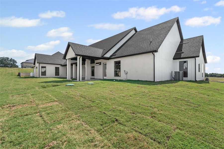 Back of property featuring a shingled roof, a yard, and a patio area Back of property featuring a shingled roof, a yard, and a patio area