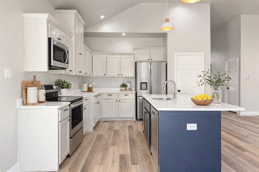 Dual tone kitchen featuring stainless steel appliances, lofted ceiling, light wood-style floors, dual tone cabinets, and decorative light fixtures Dual tone kitchen featuring stainless steel appliances, lofted ceiling, light wood-style floors, dual tone cabinets, and decorative light fixtures