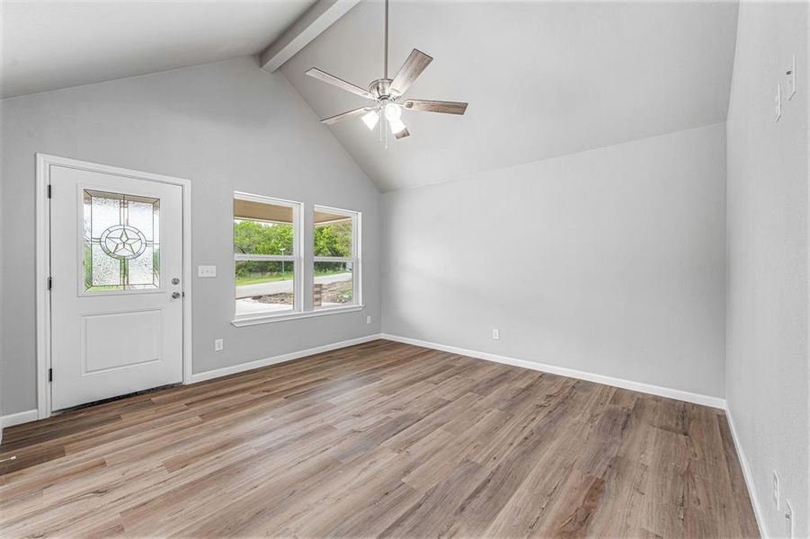 Entrance foyer with beam ceiling, light wood-type flooring, a ceiling fan, high vaulted ceiling, and baseboards Entrance foyer with beam ceiling, light wood-type flooring, a ceiling fan, high vaulted ceiling, and baseboards