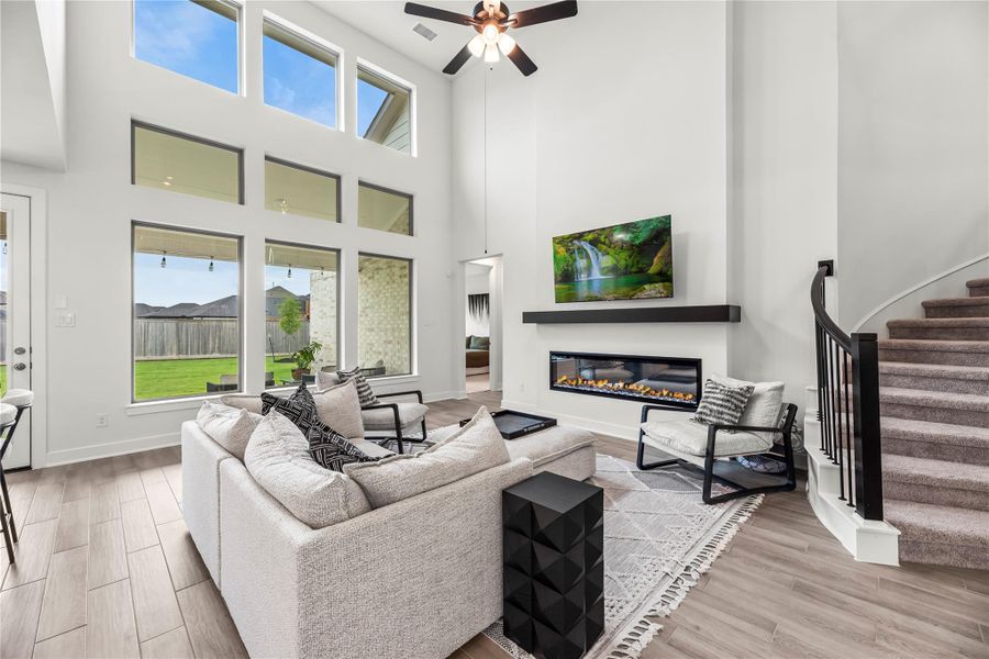 A soaring two-story ceiling, a showpiece electric fireplace, and an entire wall of stacked windows drenching the space in sunlight make this family room impossible to ignore, and nearly impossible to leave.