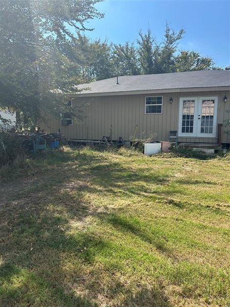 Back of house with a yard, french doors, a shingled roof, and board and batten siding