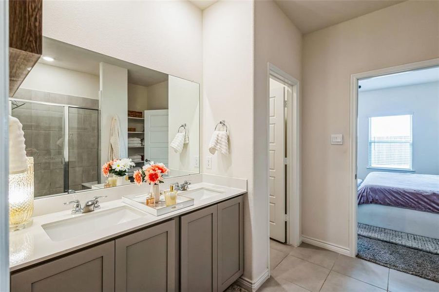 Bathroom featuring a stall shower, tile patterned flooring, a sink, and double vanity