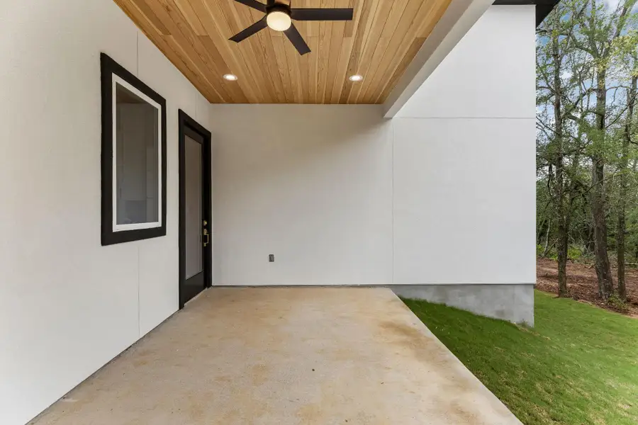 A spacious covered patio provides a serene outdoor living area adjacent to a verdant landscape.