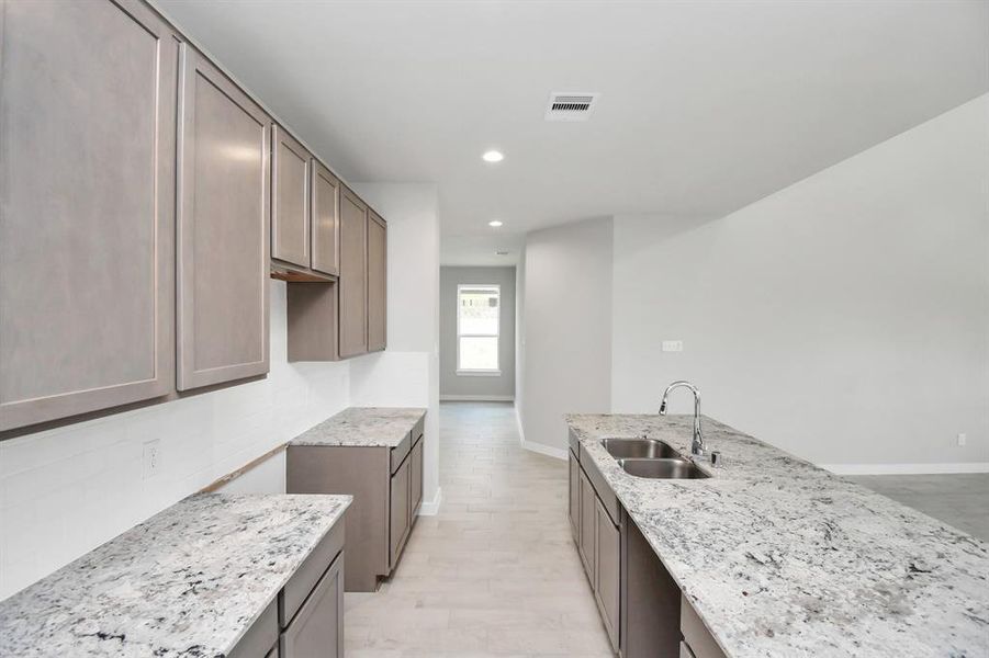 Discover another perspective of this stunning kitchen, generously appointed with an abundance of counter space. Sample photo of completed home. Actual colors and selections may vary.